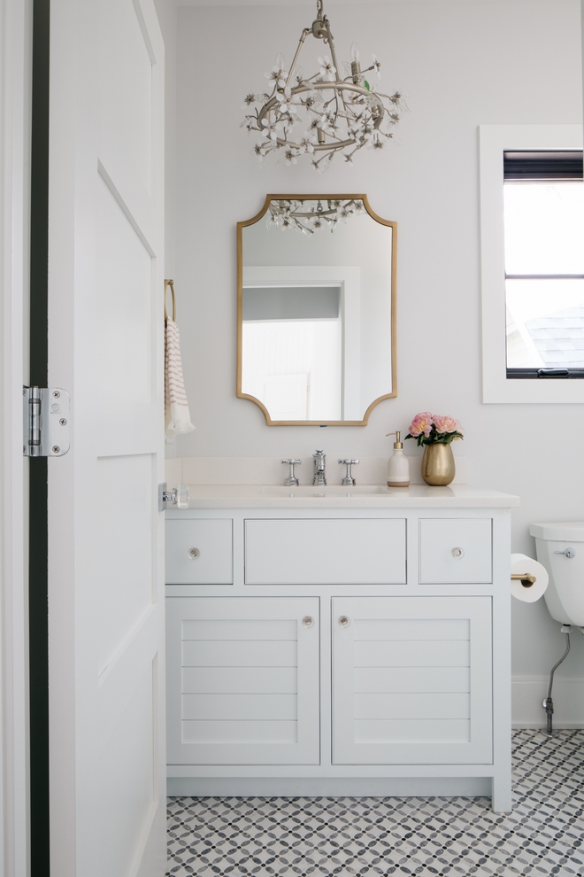 Bathroom with patterned floor, mirror, window, and flowery light fixture.