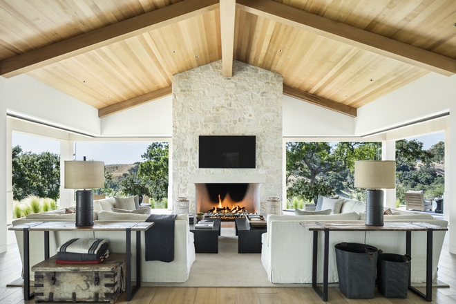 large room with fireplace, glass walls, and a vaulted ceiling