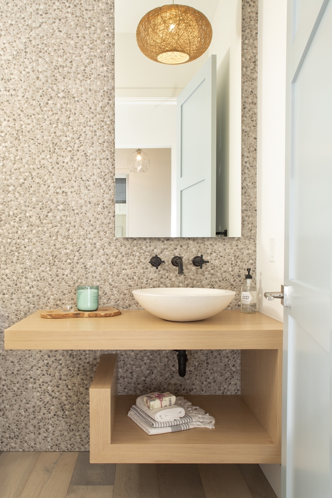 powder bathroom with pebbled wall and a floating oak vanity and a raised bowl sink