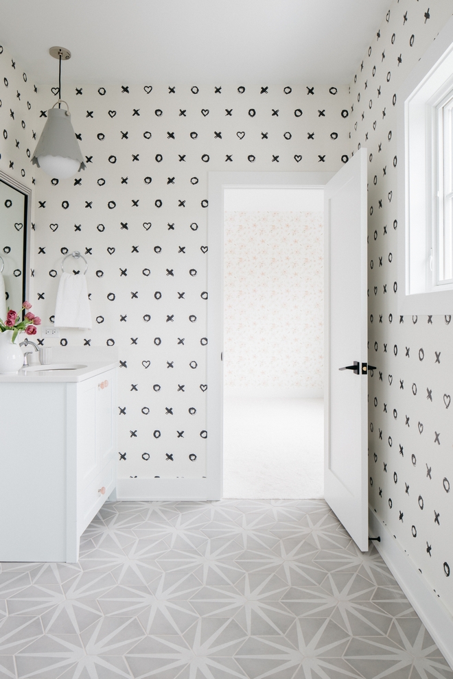 jack n jill bathroom with "xo" wallpaper and geometric floor tiling. White doors and vanity