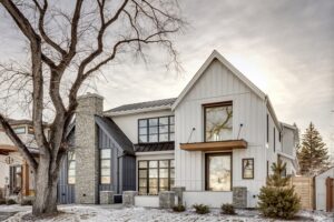 Home with white and gray paneling and stone chimney