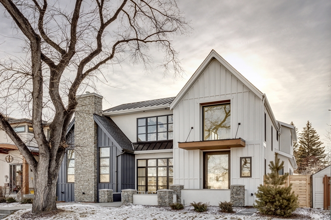 elegant farmhouse style home with white and gray paneling and stone chimney