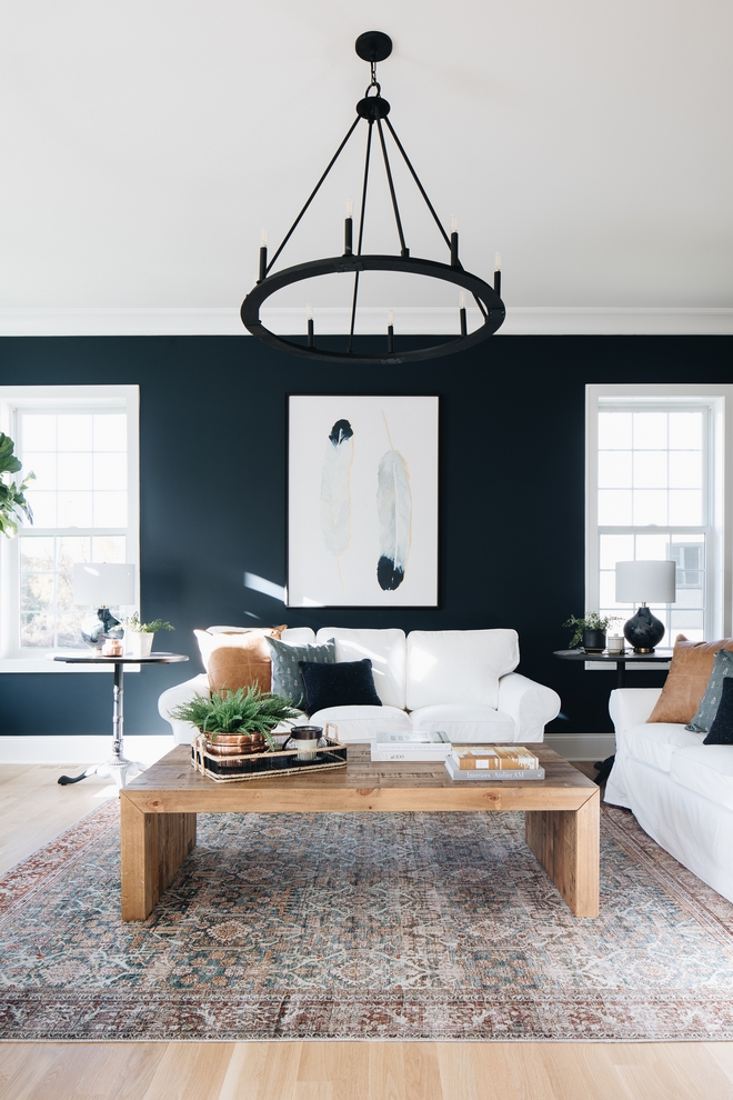 family room featuring wooden coffee table, white couch, and a round black metal candle chandelier. 