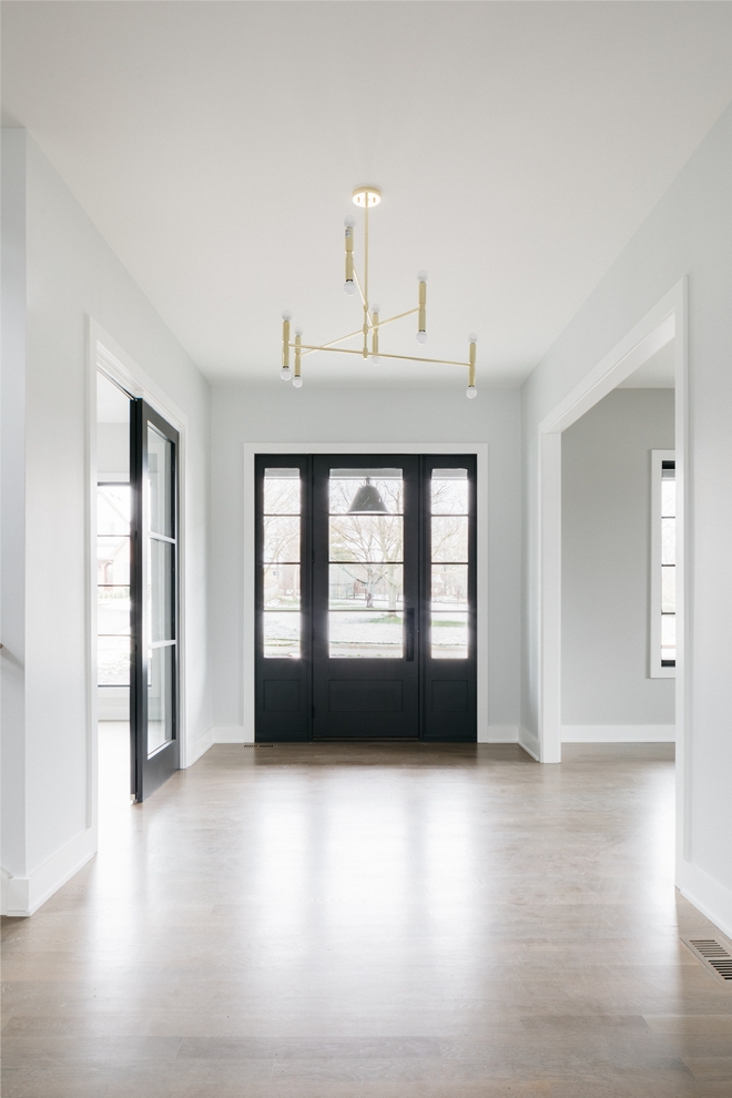 foyer of home with gray walls, white trim, and black accent door