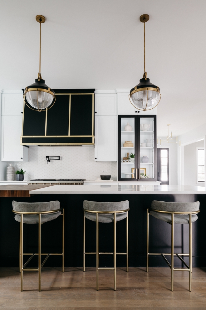 closeup of brass and gray counter stools, black island, and black stove hood. 