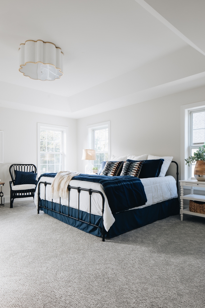 master bedroom with light walls, gray carpet and navy accent bedding