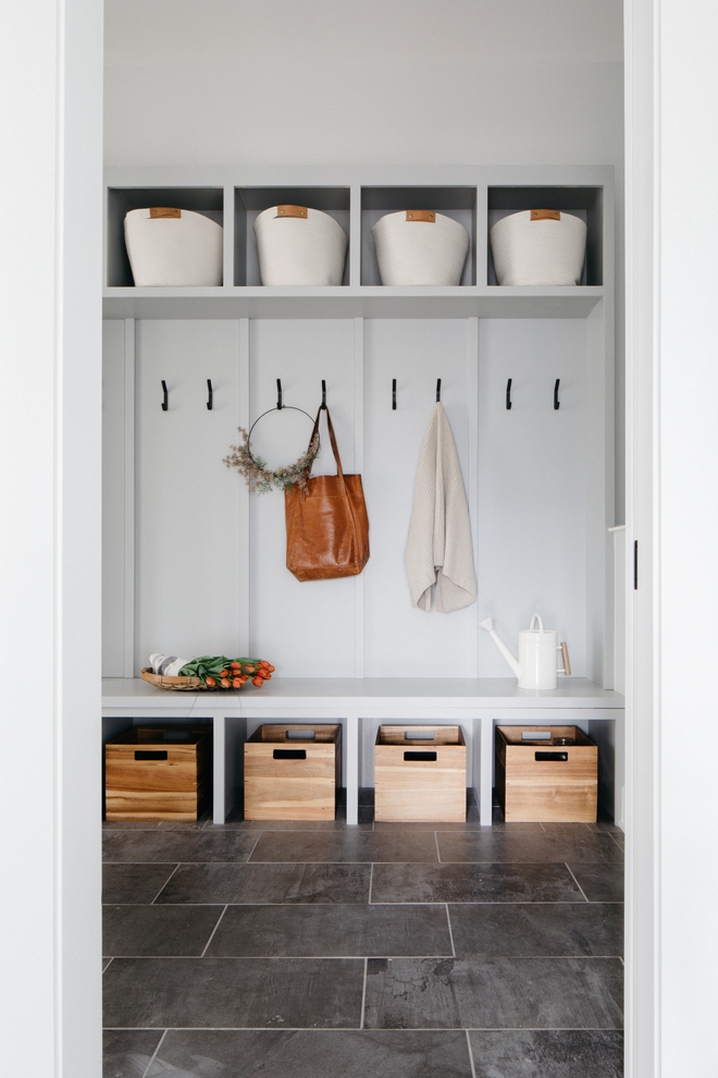 mudroom space with cubbies for baskets, a bench seat, and black hooks.
