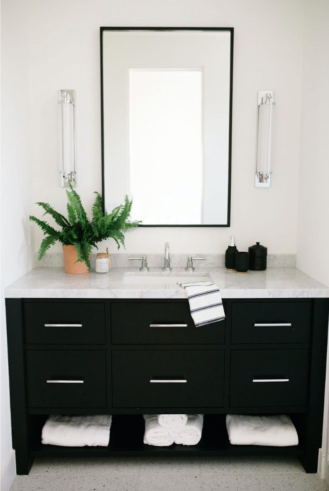 bathroom with gray countertop and flooring, black vanity, white walls, and simple mirrors and sconces.