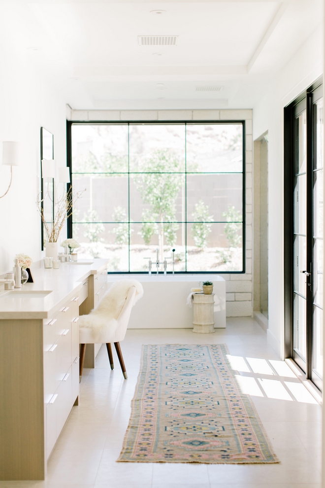 Master bathroom with natural white oak floors and vanity, limestone, a bathtub, and black-rimmed windows and doors.