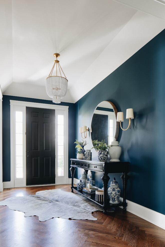 entryway to home with a black door, dark wood floors, faux skin on the floor, dark blue walls, and a black console against the wall