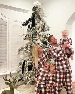 Family in Christmas PJs next to Christmas Tree